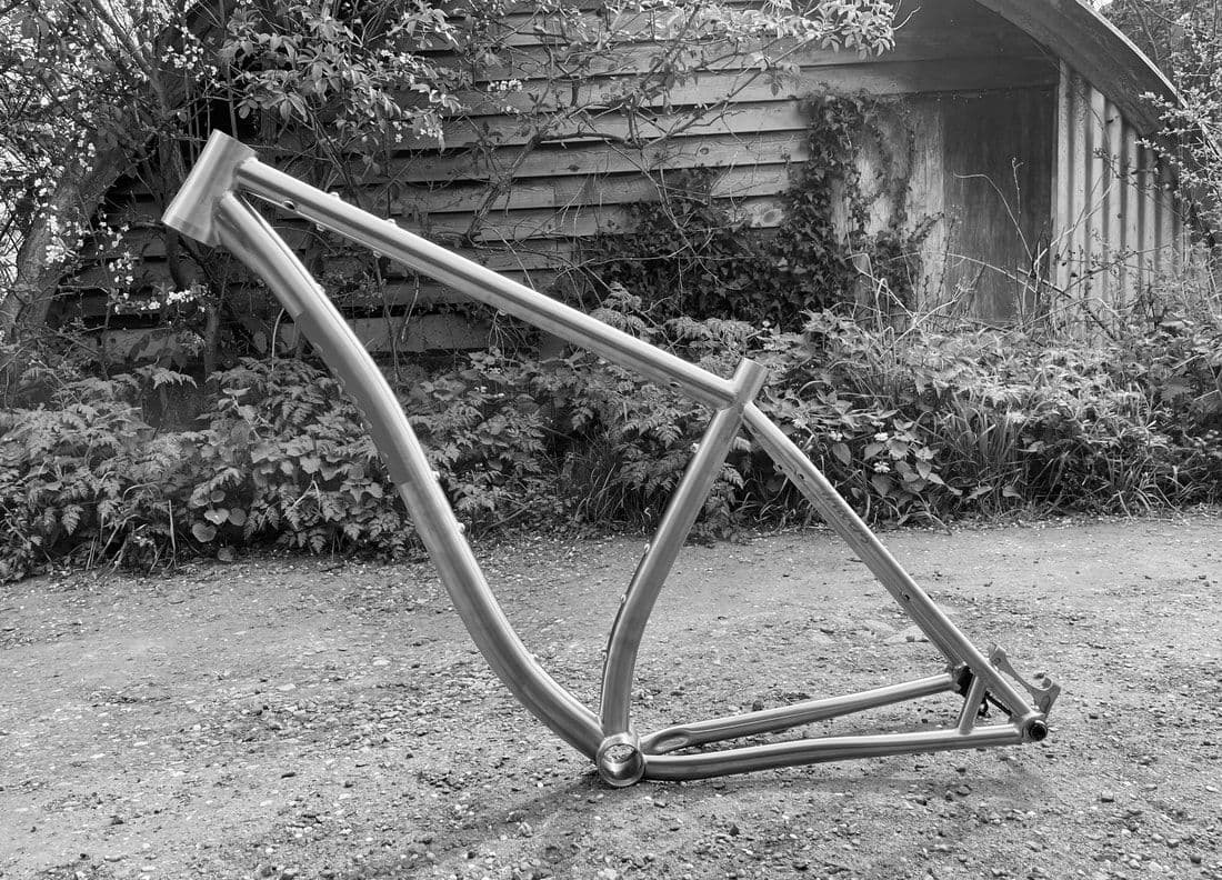 A titanium frame for a 32-inch bikepacking bike on a gravel drive