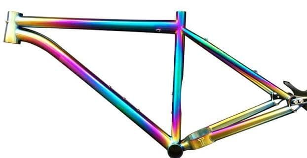 A titanium mountain bike frame with a rainbow titanium nitride finish on a white background