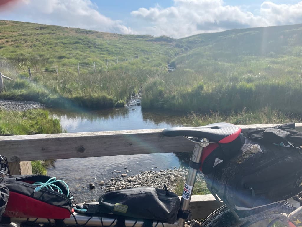 Bags on my bike, resting on a bridge over a stream on the Great British Divide