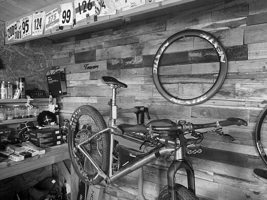 The Travers Bikes workshop: reclaimed timber wall, race number boards, a Nextie rim and a titanium bike on the bench